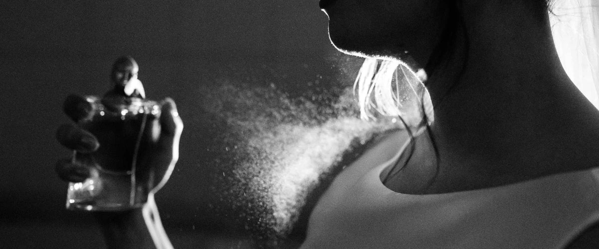 Mujer echándose perfume con fondo negro